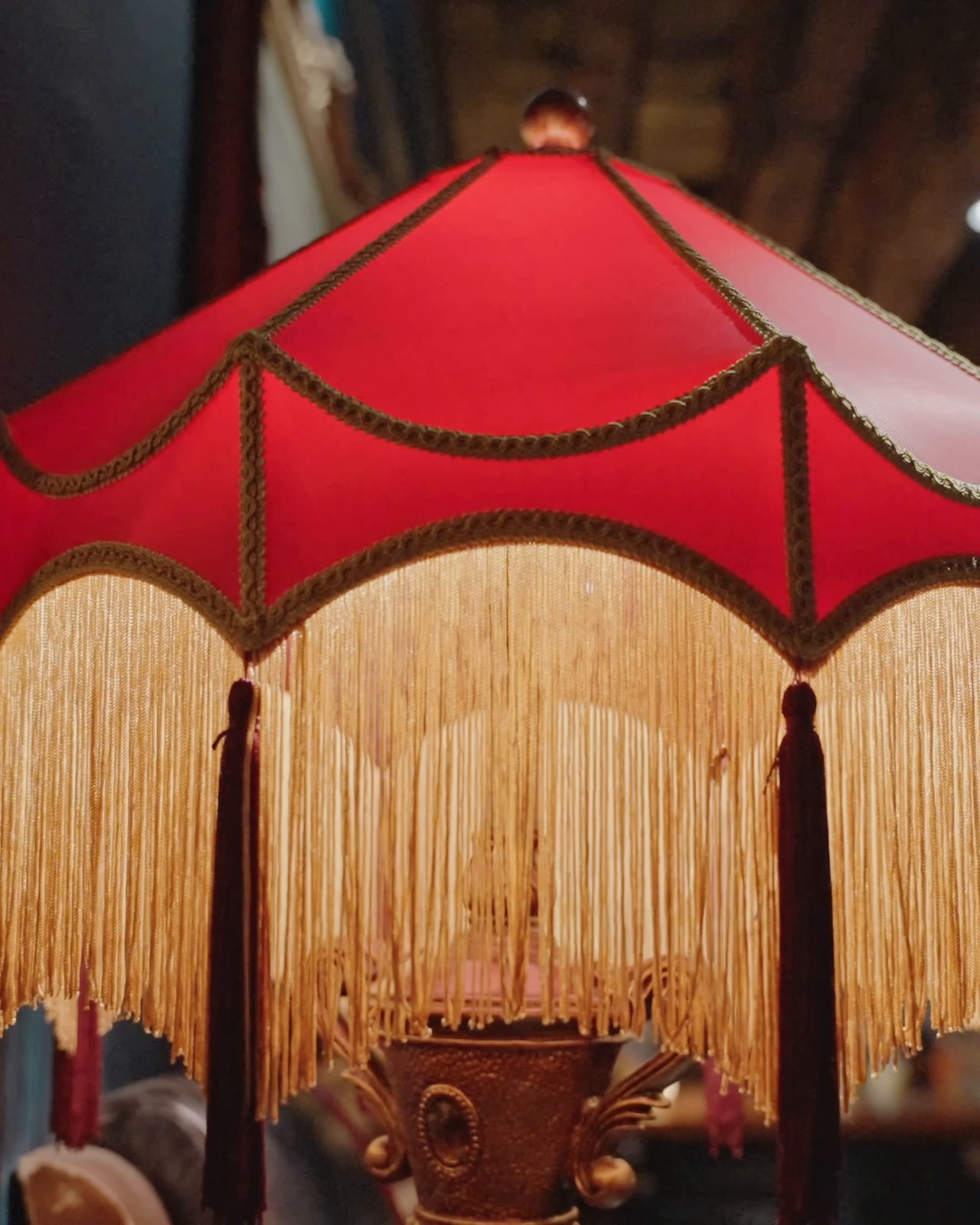 A red lamp shade with a long gold fringe