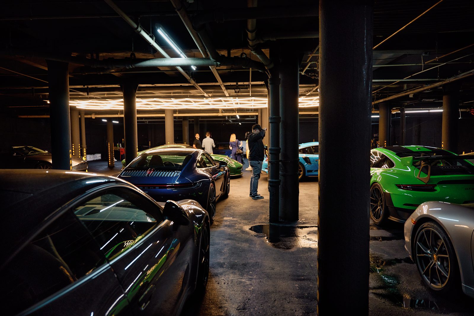 Porsches parked between the pillars of the garage, the hexagon lights beyond