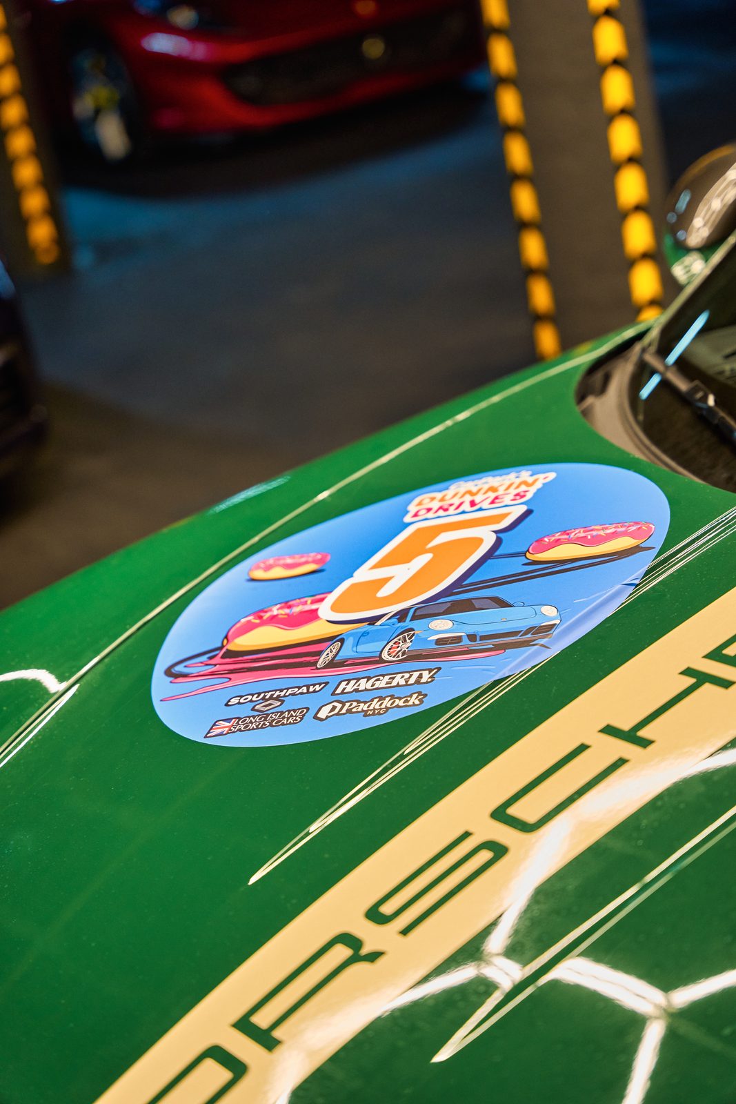 The rally's number sticker on the bonnet of a green Porsche