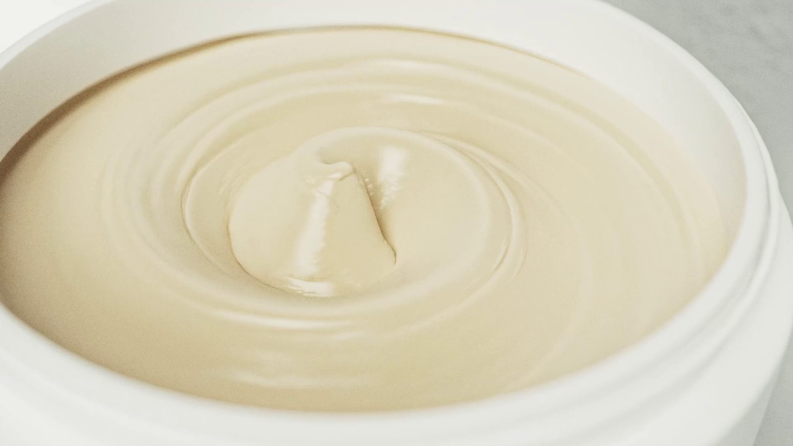 The cream in its open jar, a swirl lifted at the centre